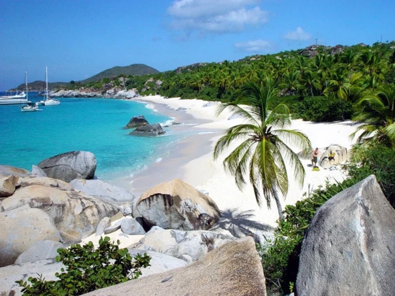 Black volcanic sand beach with lush green hills in the background